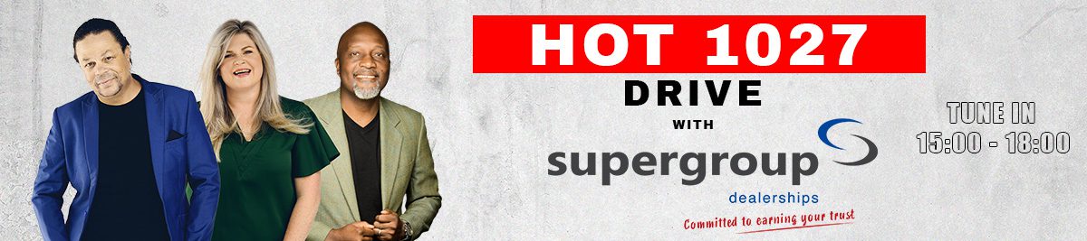 Three radio hosts stand smiling in front of the HOT 1027 Drive with Supergroup Dealerships banner. Tune in to this lively drive-time show from 15:00 to 18:00. The background is light gray with bold red and black text.